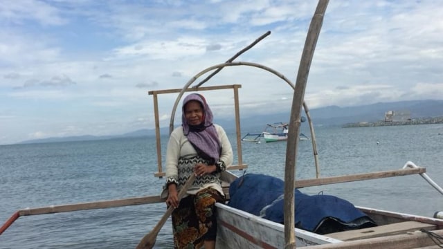 Duduk diperahunya, Rina, salah seorang nelayan perempuan di Teluk Palu, Sulawesi Tengah. Foto: Kristina Natalia/PaluPoso