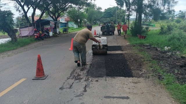 Pekerja tengah menutup lubang jalan di  jalur alternatif Brebes – Purwokerto, Jawa Tengah.