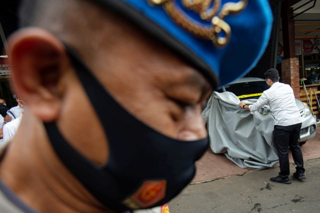 Polisi membuka kain penutup mobil yang digunakan dalam kasus penembakan anggota FPI sebelum diperiksa Komnas HAM di Polda Metro Jaya, Jakarta, Senin (21/12). Foto: Aditya Pradana Putra/ANTARA FOTO