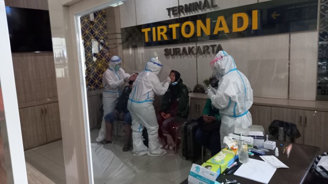 Petugas melakukan rapid test antigen kepada penumpang yang turun di Terminal Tirtonadi Solo