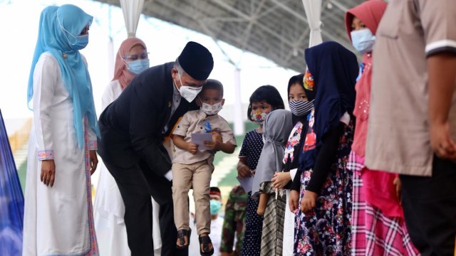 Gubernur Aceh Nova Iriansyah didampingi istri saat menyerahkan santunan kepada anak yatim pada peringatan 16 tahun tsunami, Sabtu (26/12). Foto: Suparta/acehkini