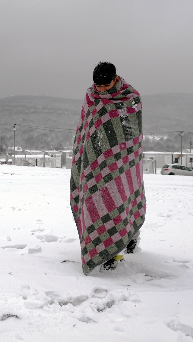 Seorang migran berjalan sambil menutupi diri dengan selimut, melewati salju di kamp Lipa barat laut Bosnia, dekat perbatasan dengan Kroasia. Foto: Kemal Softic/AP Photo