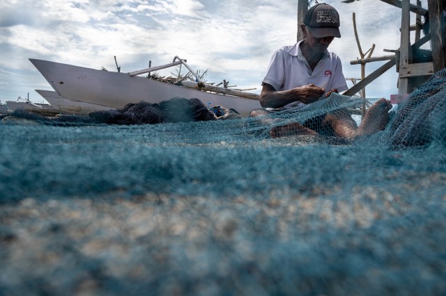 Seorang nelayan menambal pukatnya di sela-sela tidak melaut di Desa Tompe, Kabupaten Donggala, Sulawesi Tengah, Minggu (20/12/2020). Foto: Basri Marzuki/Antara Foto
