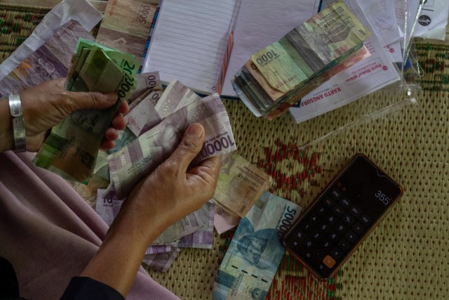 Warga menghitung uang saat menghadiri pertemuan mingguan di joglo kampung batik Giriloyo, Imogiri, Bantul, DI Yogyakarta. Foto: Hendra Nurdiyansyah/ANTARA FOTO