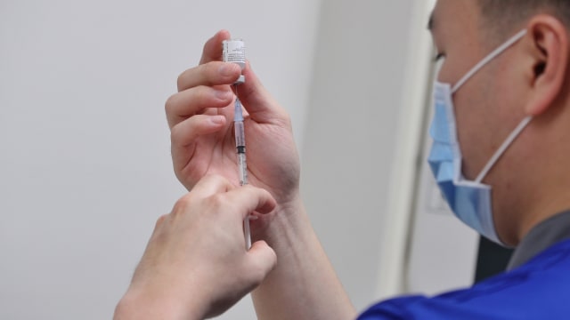 Seorang petugas bersiap memberikan vaksin corona kepada tenaga kesehatan di National Center for Infectious Diseases (NCID) di Singapura, Rabu (30/12). Foto: Ministry of Communications and Information/via Reuters