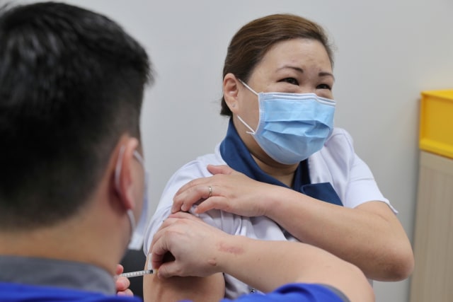 Seorang petugas kesehatan menerima vaksin corona di National Center for Infectious Diseases (NCID) di Singapura, Rabu (30/12). Foto: Ministry of Communications and Information/via Reuters