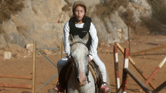 Lian Aldweek, seorang gadis Palestina yang menderita tumor tulang belakang yang menyebabkan kelumpuhan di bagian bawah tubuhnya menunggang kuda selama sesi terapi di Hebron, Israel. Foto: Mussa Qawasma/REUTERS