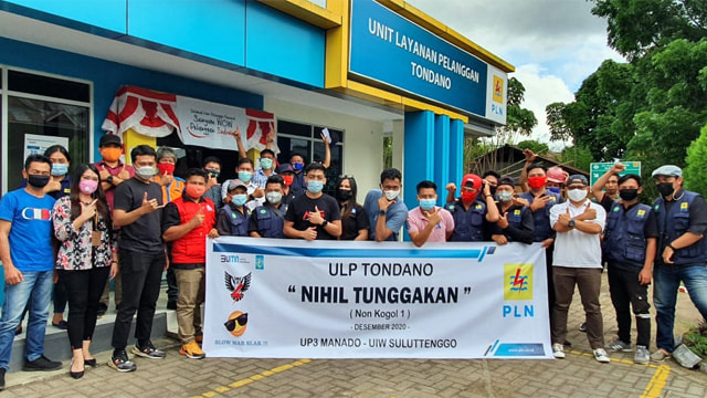 Karyawan PLN ULP Tondano berfoto bersama dengan spanduk nihil tunggakan di depan kantor pelayanan.