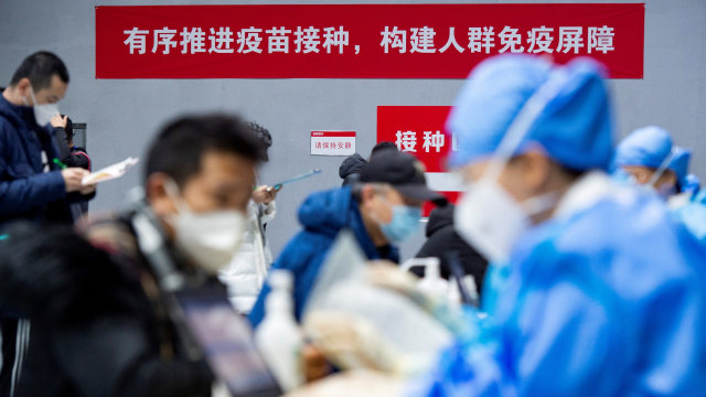 Orang-orang mengirimkan formulir untuk menerima vaksin corona di pusat vaksinasi sementara, Beijing, China, Minggu (3/1).  Foto: cnsphoto/via REUTERS