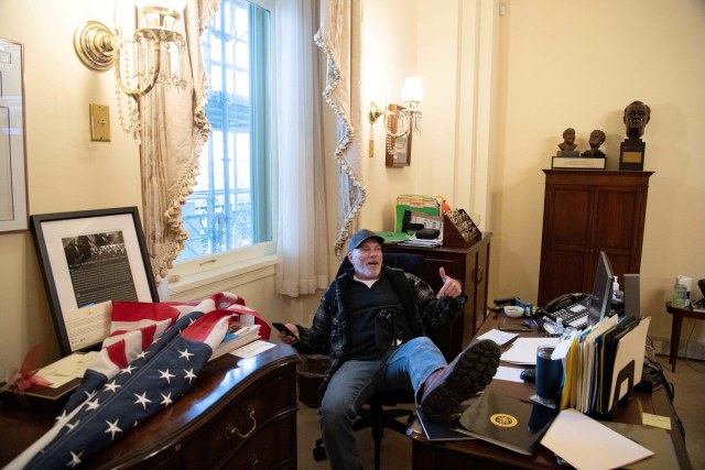 Seorang pendukung Presiden AS Donald Trump duduk di dalam kantor Ketua DPR AS Nancy Pelosi saat ia melakukan protes di dalam US Capitol di Washington, DC. Foto: AFP