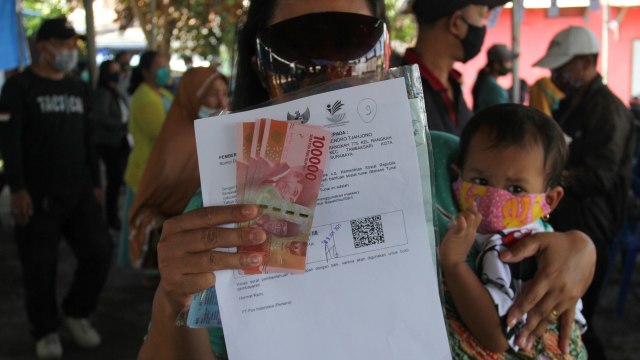 Warga menunjukkan uang Bantuan Sosial Tunai (BST) yang diperolehnya. Foto: ANTARA FOTO/Didik Suhartono