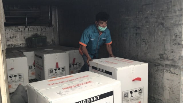 PETUGAS mendorong paket berisikan Vaksin Virus Corona yang baru tiba di Pekanbaru, Selasa (5/1/2021). 