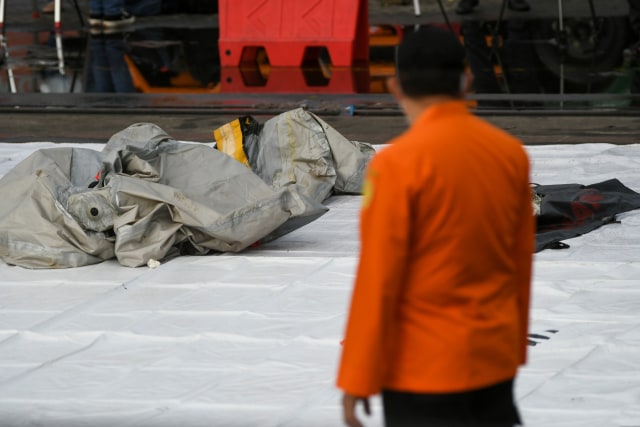 Petugas Basarnas memeriksa benda yang diduga serpihan dari pesawat Sriwijaya Air SJ 182 rute Jakarta - Pontianak yang hilang kontak di perairan Pulau Seribu, di Dermaga JICT, Jakarta, Minggu (10/1).  Foto: Galih Pradipta/ANTARA FOTO