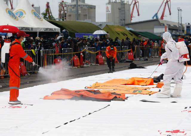 Seorang anggota Palang Merah Indonesia menyemprotkan disinfektan di area Dermaga JICT, Tanjung Priok, Jakarta Utara. Foto: Ajeng Dinar Ulfiana/Reuters
