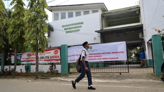 Seorang siswa sekolah lain melintas di depan SD Muhammadiyah 2 Banda Aceh yang ditutup karena langgar protokol kesehatan corona. Foto: Suparta/acehkini