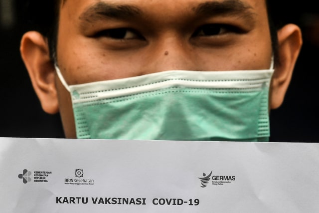 Seorang pasien menunjukkan kartu vaksinasi COVID-19 saat simulasi pemberian vaksin corona Sinovac di Puskesmas Kelurahan Cilincing I, Jakarta, Selasa (12/1).  Foto: Muhammad Adimaja/ANTARA FOTO