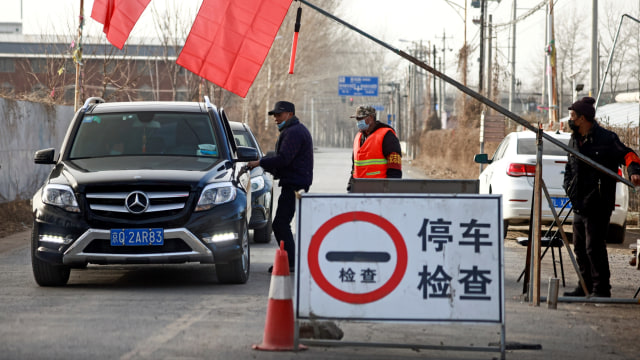 Relawan berdiri di pos pemeriksaan di jalan menuju desa di provinsi Hebei, China.  Foto: Thomas Peter/REUTERS