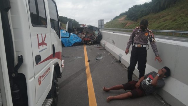 SEORANG korban sedang dihibur anggota Lantas usai tabrakan menewaskan satu keluarga di KM 32 Jalan Tol Pekanbaru-Dumai, Rabu (13/1/2021). 