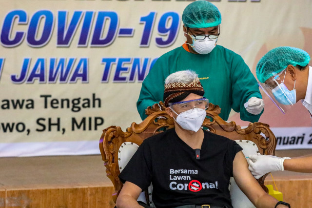 Gubernur Jawa Tengah Ganjar Pranowo (kiri) disuntik vaksin corona Sinovac oleh vaksinator dokter senior spesialis penyakit dalam Zulfachmi Wahab di RSUD Tugurejo, Semarang, Jawa Tengah, Kamis (14/1). Foto: Humas Pemprov Jateng-Arif Slam/HO ANTARA FOTO