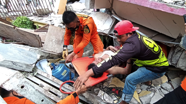 Petugas mengevakuasi korban yang terjepit bangunan di rumah sakit Mitra Manakarra yang runtuh akibat gempa bumi di Mamuju, Sulawesi Barat, Kamis (15/1). Foto: Akbar Tado/ANTARA FOTO