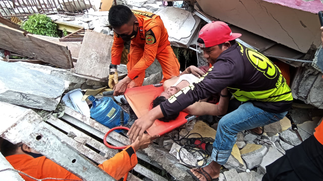 Petugas mengevakuasi korban yang terjepit bangunan di rumah sakit Mitra Manakarra yang runtuh akibat gempa bumi di Mamuju, Sulawesi Barat, Kamis (15/1).  Foto: Akbar Tado/ANTARA FOTO