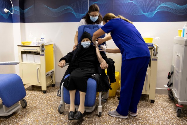 Seorang wanita lanjut usia saat menerima vaksin virus corona di rumah sakit Evangelismos di Athena, Yunani. Foto: Alkis Konstantinidis/Reuters