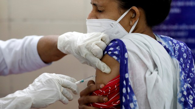 Seorang petugas kesehatan bereaksi ketika dia menerima dosis vaksin corona COVISHIELD di sebuah pusat kesehatan di Jetalpur di pinggiran kota. Ahmedabad, India, Sabtu (16/1). Foto: Amit Dave/Reuters