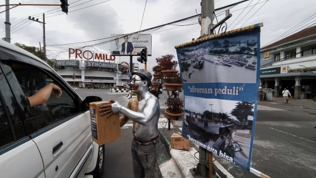 Manusia Perak alias Silverman menggalang dana di Jalan Kayutangan Kota Malang untuk korban bencana banjir bah di Kalimantan Selatan, pada Senin (18/1/2021). Foto: Ulul Azmy