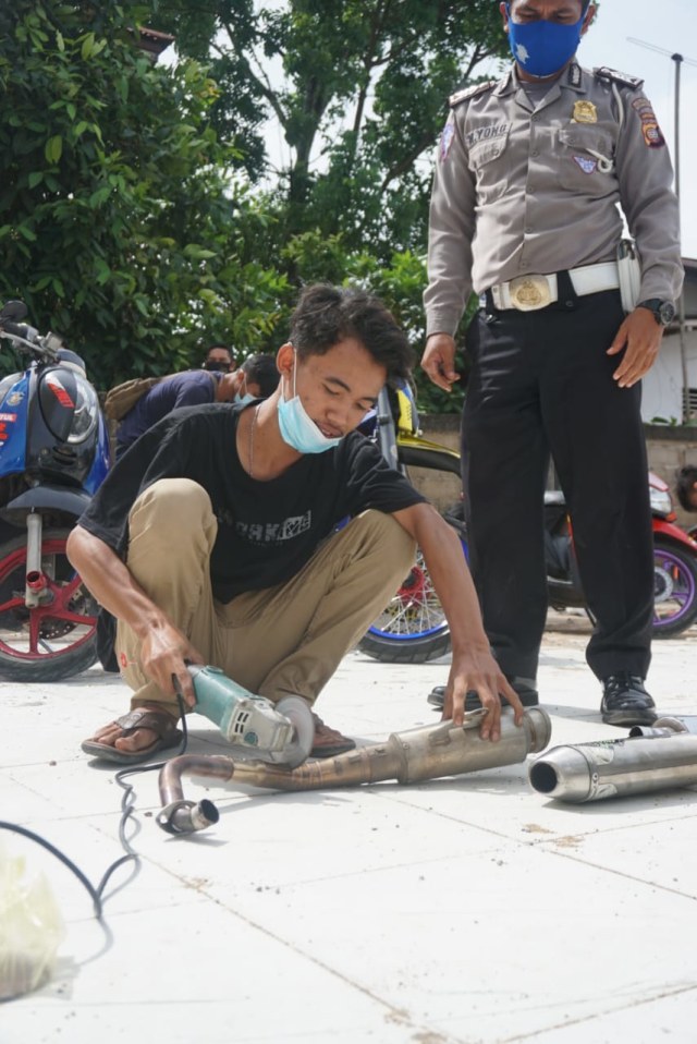 Seorang pemilik sepeda motor memotong knalpot racing mereka. Foto: Dok Humas Polresta Pontianak