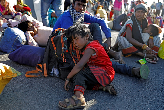 Seorang anak pekerja migran tertidur di jalan raya karena gagal mendapatkan bus untuk kembali ke desa mereka selama penguncian nasional di New Delhi, India pada 29 Maret 2020. Foto: Adnan Abidi/REUTERS