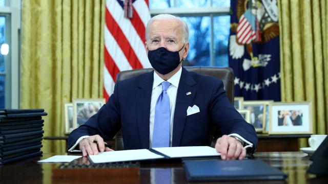 Presiden AS Joe Biden menandatangani perintah eksekutif di Ruang Oval Gedung Putih, Washington, AS. Foto: Tom Brenner/REUTERS