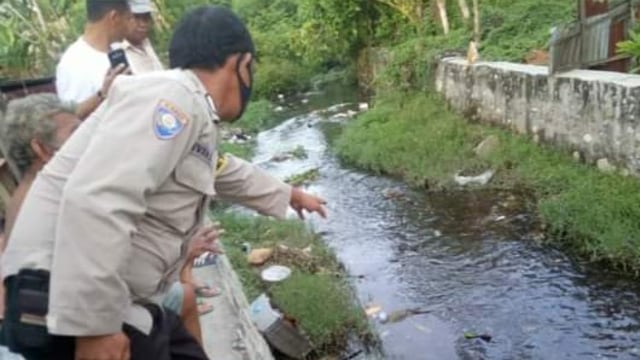 Seorang Polisi di Labuan, Donggala, Sulteng, menunjukkan lokasi penemuan mayat bayi di selokan Desa Wani 2, Kecamatan Tanantovea, Kabupaten Donggala. Foto: Istimewa
