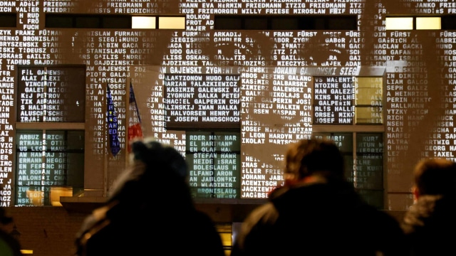 Orang-orang menyaksikan di instalasi lampu bernama #everynamecounts yang memproyeksikan nama-nama korban rezim Nazi di Berlin, Jerman, Jumat (22/1/2021). Foto: Fabrizio Bensch/REUTERS