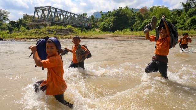 Siswa di Gampong Panca Kubu, Lembah Seulawah, Kabupaten Aceh Besar, menyeberangi sungai saat pulang sekolah pada Jumat (22/1). Foto: Suparta/acehkini