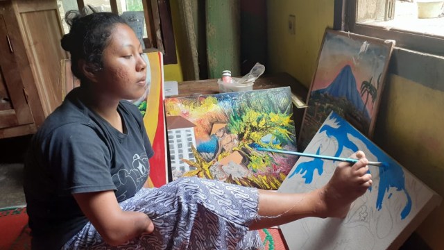 Puji Lestari, wanita di Gunungkidul yang tidak memiliki tangan sempurna melukis di atas kanvas dengan kakinya. Foto: Erfanto/Tugu Jogja.