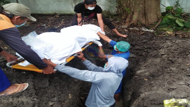 Petugas saat lakukan pemakaman mayat laki-laki yang ditemukan mengapung di aliran sungai Bengawan Solo, Baureno Kabupaten Bojonegoro. (foto: istimewa)