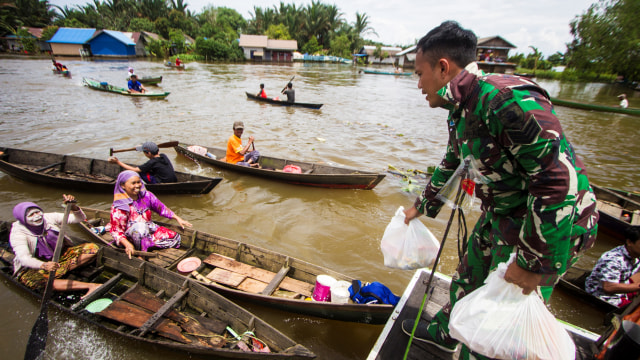 Anggota TNI AD memberikan bantuan sembako kepada warga yang terdampak banjir di Kabupaten Banjar, Kalimantan Selatan, Selasa (26/1).  Foto: Bayu Pratama S/ANTARA FOTO
