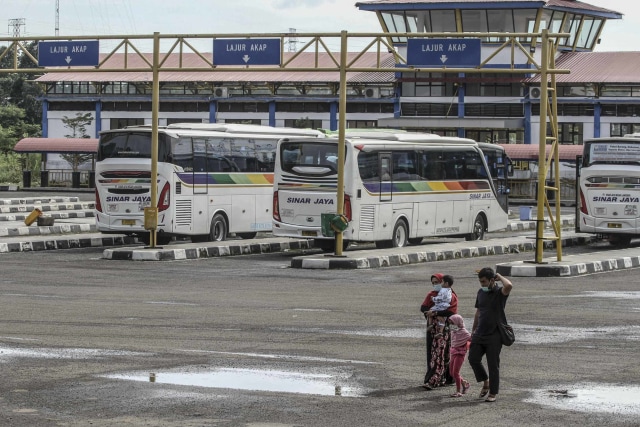 Sejumlah penumpang melintasi area parkir bus di Terminal Jatijajar, Depok, Jawa Barat, Kamis (28/1/2021). Foto: Asprilla Dwi Adha/ANTARA FOTO