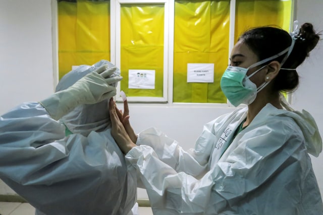 Seorang tenaga kesehatan membantu rekannya merapikan alat pelindung diri (APD) sebelum melakukan perawatan pasien COVID-19 di Rumah Sakit Darurat (RSD) COVID-19, Wisma Atlet Kemayoran, Jakarta. Foto: M Risyal Hidayat/ANTARA FOTO