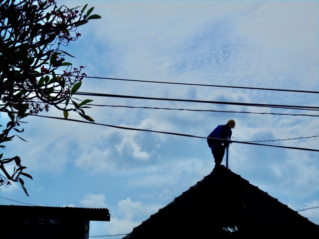 Seorang petugas Pelayanan Teknik PLN Yogyakarta sedang melakukan perbaikan jaringan listrik di salah satu rumah pelanggan, Selasa (26/1).  Foto: Widi Erha Pradana. 