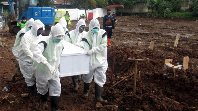 Petugas pemakaman membawa peti jenazah korban COVID-19. Foto: Yulius Satria Wijaya/ANTARA FOTO