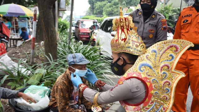 Polisi berkostum wayang membagikan masker kepada pembeli dan pedagang di pasar tradisional di Solo