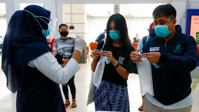 Sejumlah penumpang memberikan kantong plastik berisi sampel udaranya untuk diuji menggunakan alat pendeteksi corona GeNose di sebuah stasiun kereta api di Jakarta, Indonesia, Rabu (3/2). Foto: Ajeng Dinar Ulfiana/REUTERS