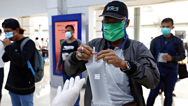 Seorang pria memberikan kantong plastik berisi sampel udaranya untuk diuji menggunakan alat pendeteksi corona GeNose di sebuah stasiun kereta api di Jakarta, Indonesia, Rabu (3/2). Foto: Ajeng Dinar Ulfiana/REUTERS