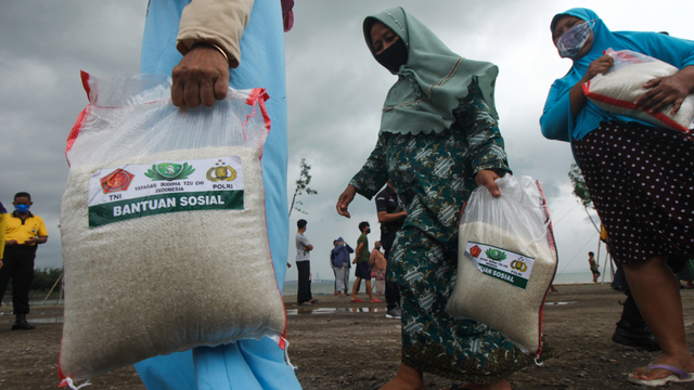 Warga membawa paket beras bantuan. Foto: ANTARA FOTO/Didik Suhartono