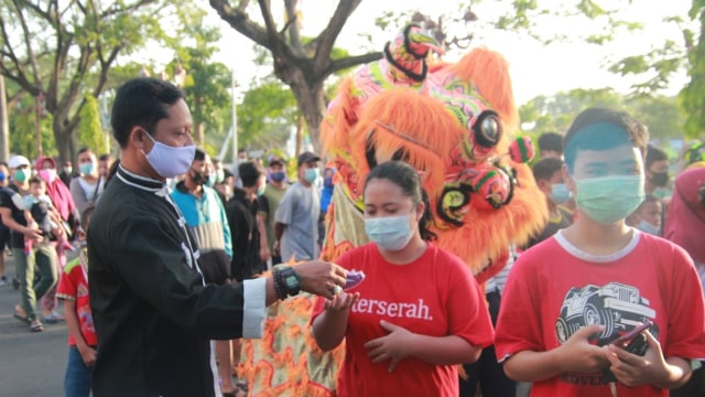 Sosialiasi protokol kesehatan dan pembagian masker oleh barongsai di Lamongan, Jawa Timur, Minggu (7/2). Foto: Pendam TNI