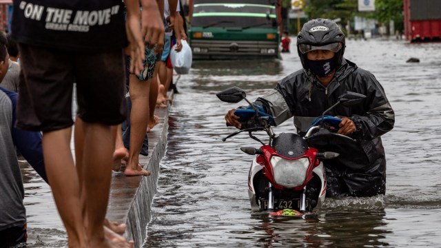 Warga mendorong sepeda motornya yang mogok akibat menembus jalur Pantura Jalan Raya Kaligawe - Genuk yang terendam banjir di Genuk, Semarang, Jawa Tengah, Senin (8/2). Foto: Aji Styawan/ANTARA FOTO