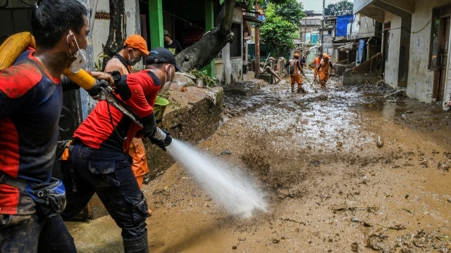 Petugas pemadam kebakaran bersama warga menyemprotkan air untuk membersihkan endapan lumpur sisa banjir di kawasan Pejaten Timur, Pasar Minggu, Jakarta, Selasa (9/2). Foto: Galih Pradipta/ANTARA FOTO