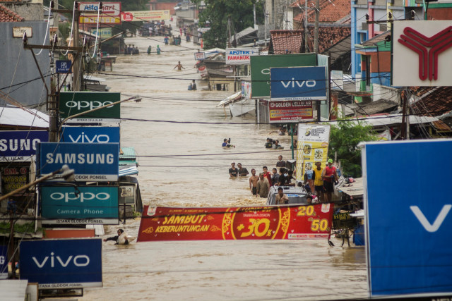 Warga melintasi jalan raya yang terendam banjir saat proses evakuasi di Pamanukan, Kabupaten Subang, Jawa Barat, Selasa (9/2). Foto: Novrian Arbi/ANTARA FOTO