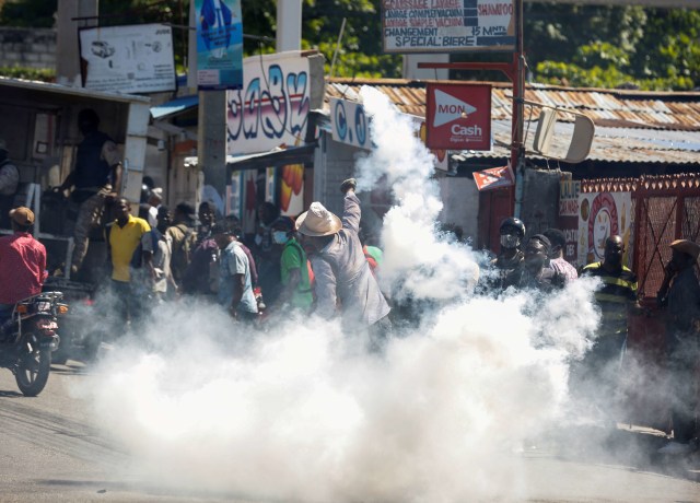 Seorang pria melemparkan tabung gas air mata ke arah polisi saat protes terhadap Presiden Haiti Jovenel Moise, di Port-au-Prince, Haiti. Foto: Jeanty Junior Augustin/Reuters